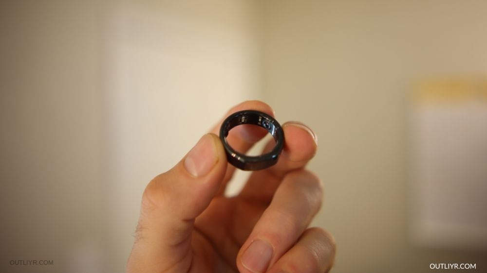 A closeup of a man holding an Oura Ring Generation 3